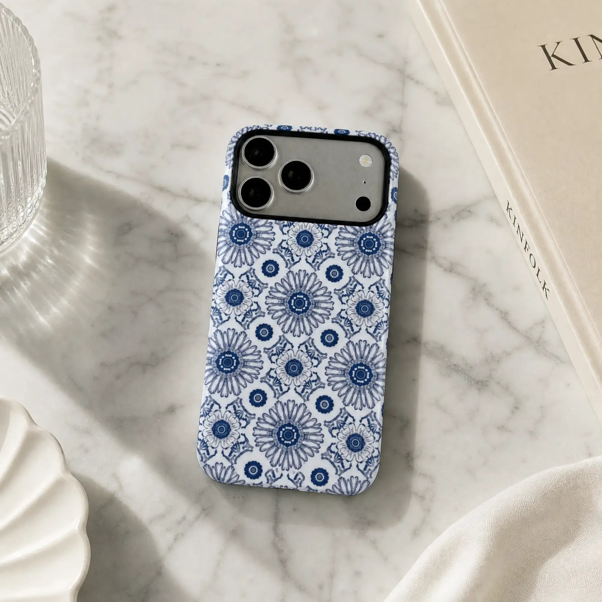 Blue Heritage Kaleidoscope matte case on iPhone 17 Pro Max, displayed on a minimalist concrete plinth with soft natural light and shadows.
