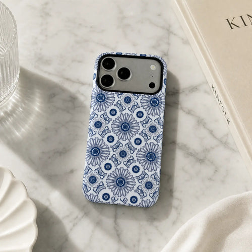 Blue Heritage Kaleidoscope matte case on iPhone 17 Pro Max, displayed on a minimalist concrete plinth with soft natural light and shadows.