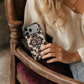 Burgundy Damask matte case on iPhone 17 Pro Max, styled with vintage dark wood and a minimalist brass compass on a clean studio surface.