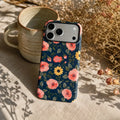 Navy Peach Floral matte case on iPhone 17 Pro Max, styled with a minimalist brass tray and a single dried flower on a dark oak desk.