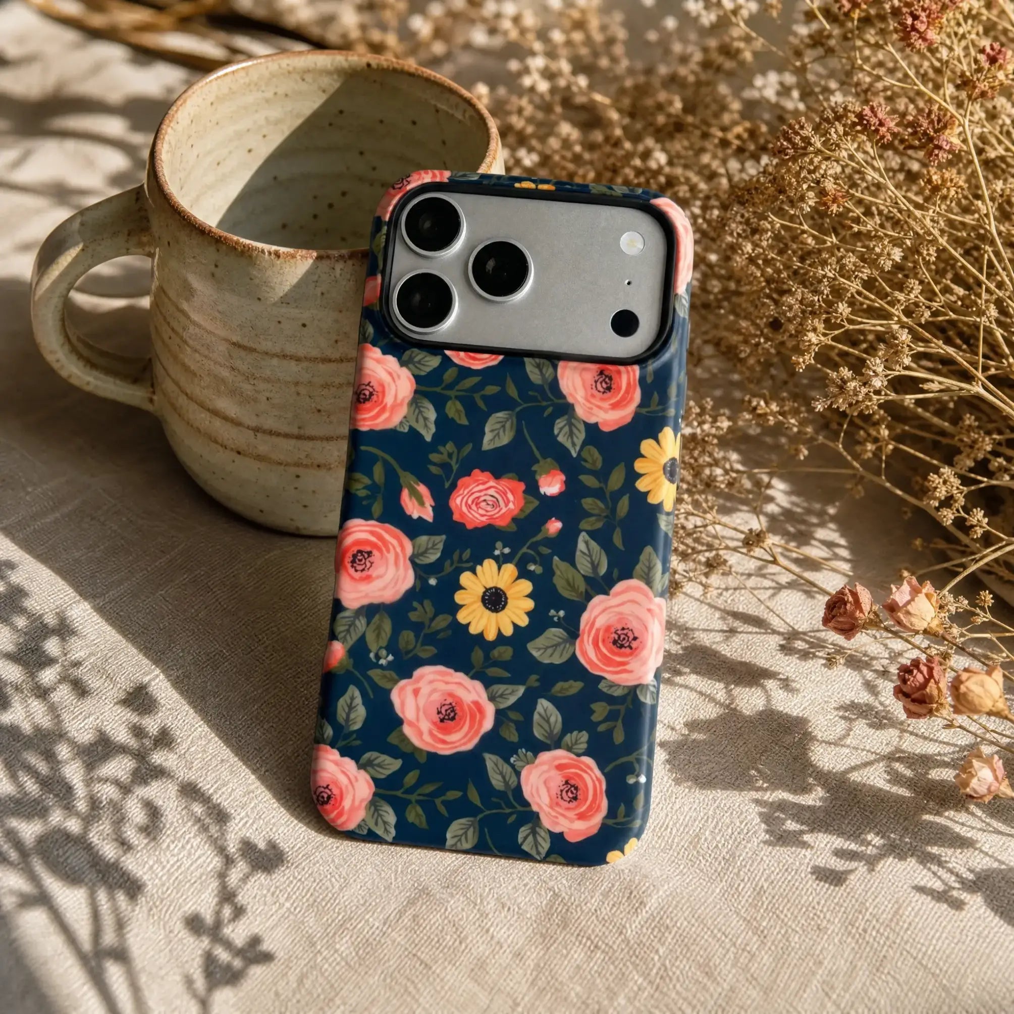 Navy Peach Floral matte case on iPhone 17 Pro Max, styled with a minimalist brass tray and a single dried flower on a dark oak desk.