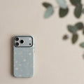 Mewvia Sage Green line art wildflower iPhone 17 Pro Max case in a minimalist lifestyle setting with soft natural lighting.
