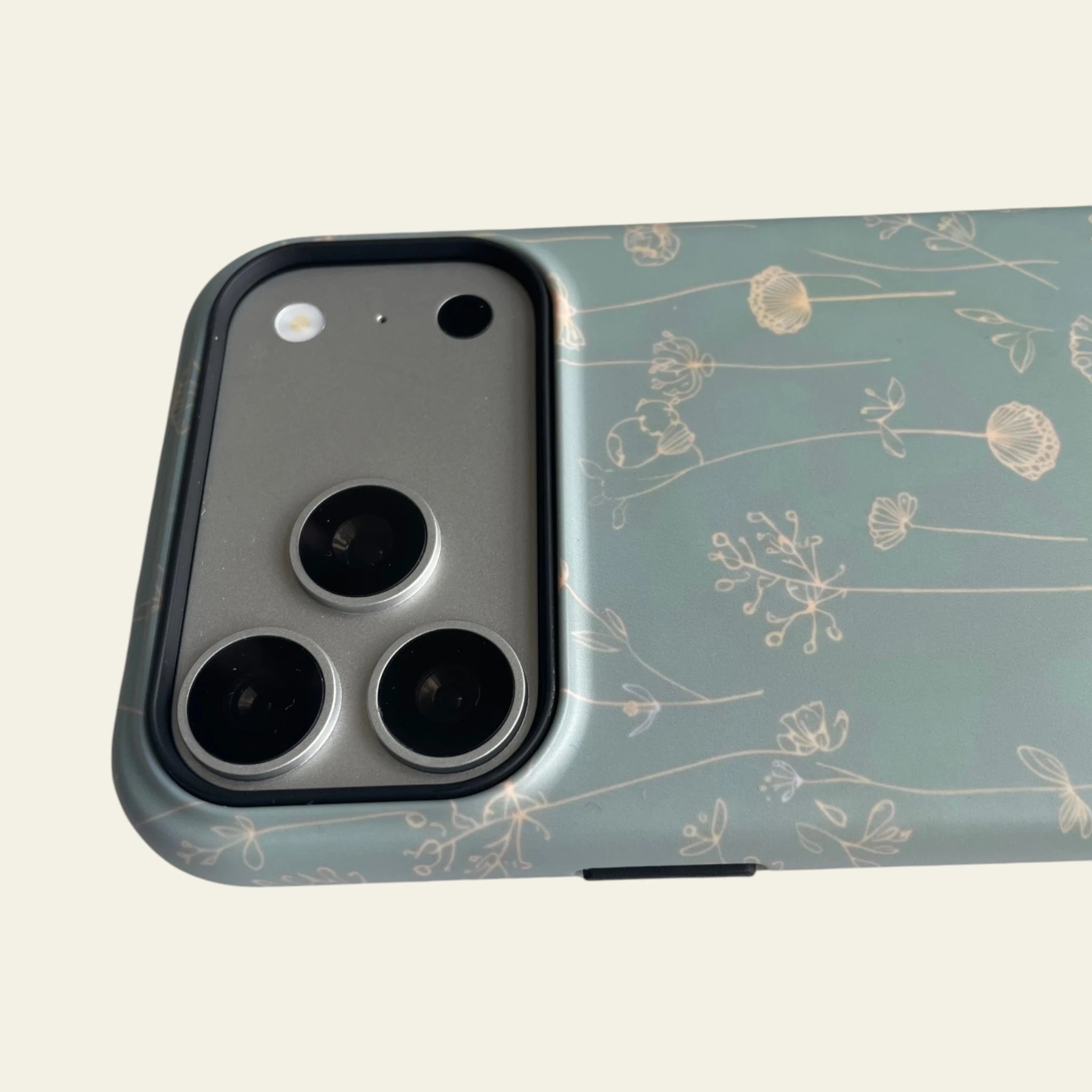 Close-up of the premium matte texture and delicate wildflower line art on the Sage Green iPhone 17 Pro Max case.
