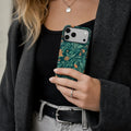 William Morris inspired floral matte case on iPhone 17 Pro Max, styled with vintage leather books and soft shadows on a minimalist stone surface.